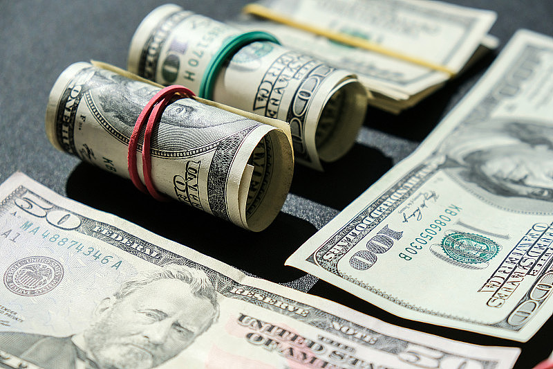 在美元的背景下，美元bundle紧密孤立。纸制的美元钞票卷着橡皮筋。事业预算，财富理财，繁荣理财