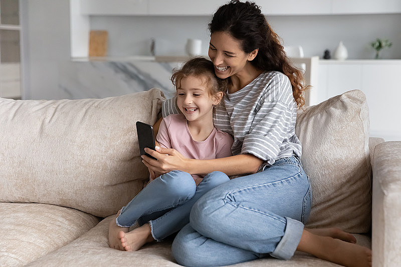 快乐的年轻妈妈和小孩使用手机应用程序。