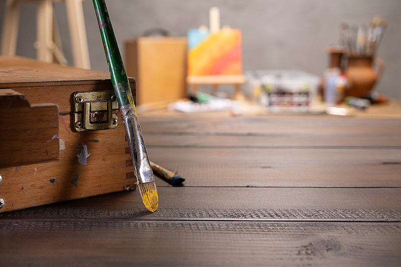 木桌上有画笔和艺术工具。桌上有画笔和油漆工用品