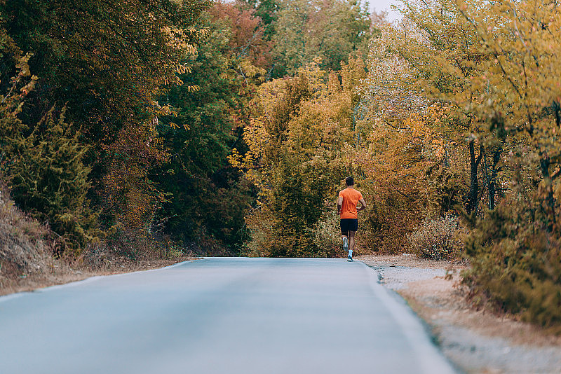 跑步运动员在森林小道上跑步。男士健身慢跑健身养生理念