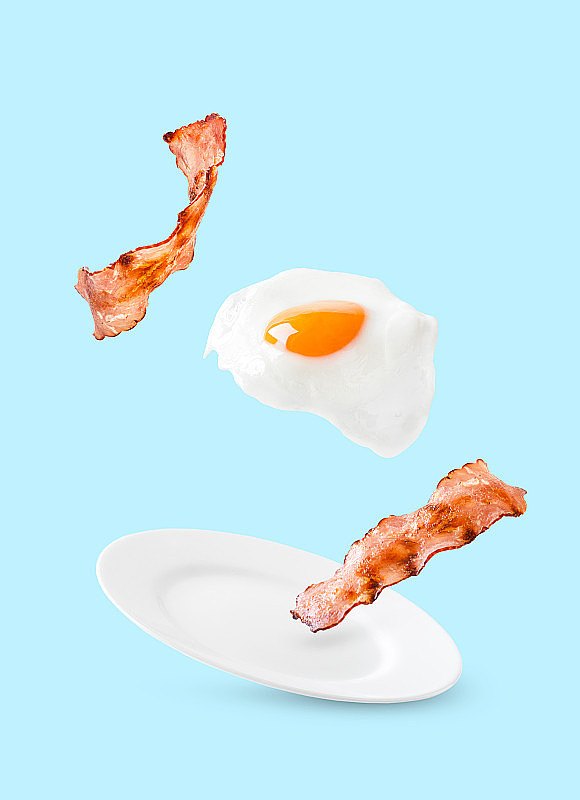 培根和鸡蛋作为英式早餐漂浮在蓝色背景的盘子上