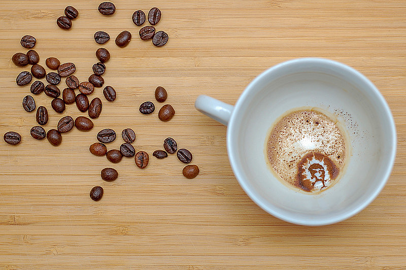 咖啡渣上的算命，印有男人头像的咖啡杯，木桌上的咖啡粒