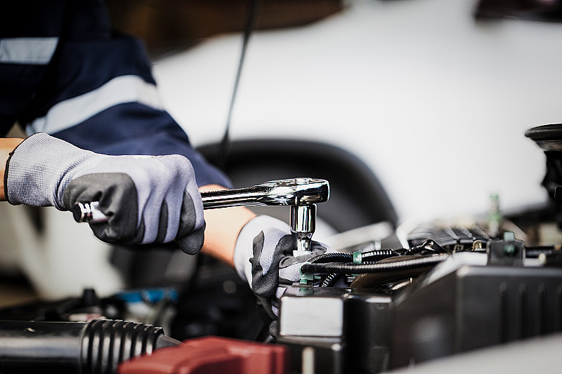 专业的技工正在修车厂修理汽车的发动机。汽车修理服务。
