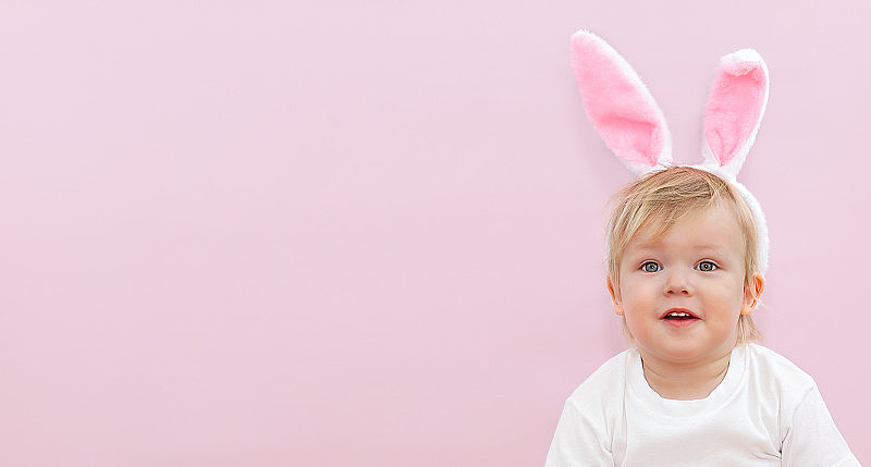 粉红色背景上长着兔耳朵的可爱宝宝。