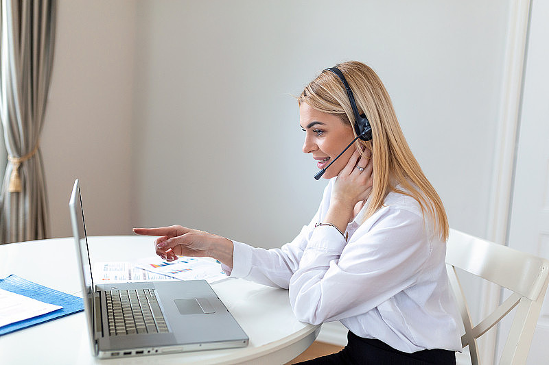 年轻友好的接线员，戴着耳机的女代理。美丽的商务女性戴着麦克风耳机在办公室工作，作为一名电话营销客服代理，呼叫中心的工作理念。