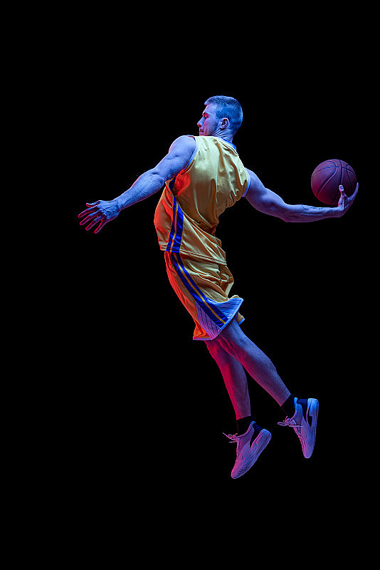 人像运动的人，职业篮球运动员打篮球孤立在黑暗的背景霓虹灯。成就、运动事业、运动理念。