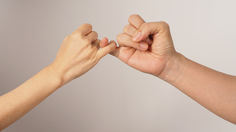男人和女人做小指承诺或小指发誓的手在白色背景上签字。