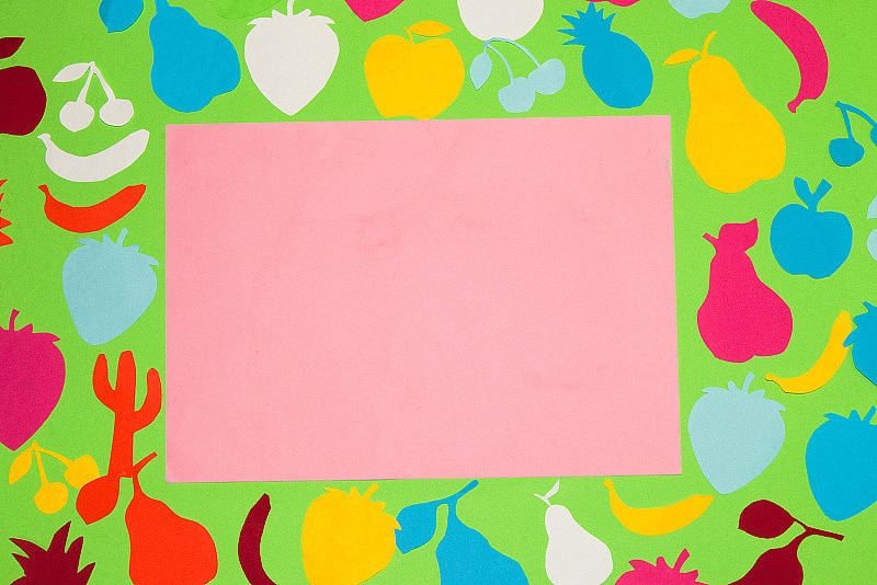 绿色的底色用彩色的纸水果在中间粉红色的纸作为拷贝空间，创意艺术夏天的设计，时间为维生素