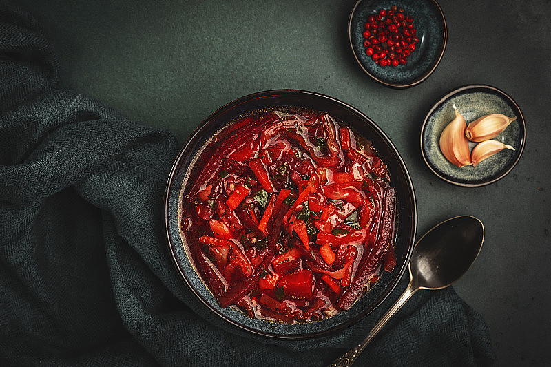 传统的自制红白菜汤与甜菜，蔬菜和草药，俄罗斯罗宋汤在蓝色厨房餐桌背景，俯视图，复制空间。纯素，素食健康饮食食品