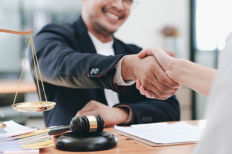 商人与合作伙伴律师或讨论合同协议的律师握手以达成协议。
