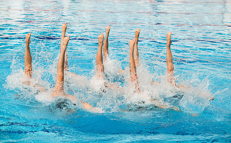 花样游泳运动员在例行活动中手臂伸出水池
