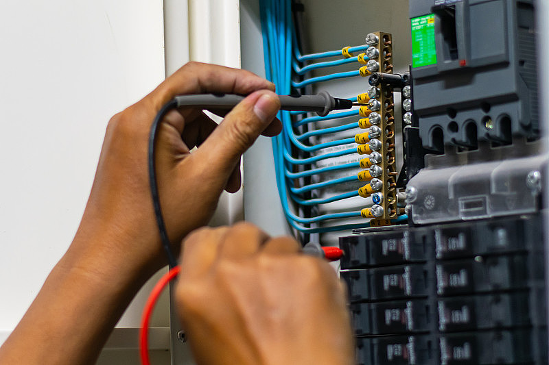 电工工作测试仪在电气控制柜中测量电力线路的电压和电流，专业人员使用工具调试测试或检查保护系统的电路。