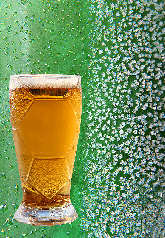 啤酒玻璃上的冰晶和滴绿色背景。