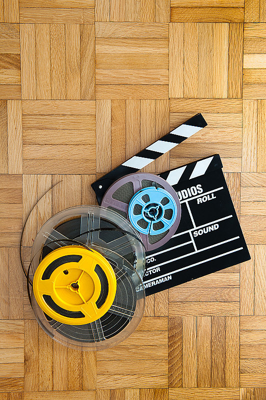 木地板上的电影拍板和胶片卷轴