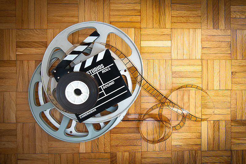 木地板上的电影拍板和胶片卷轴