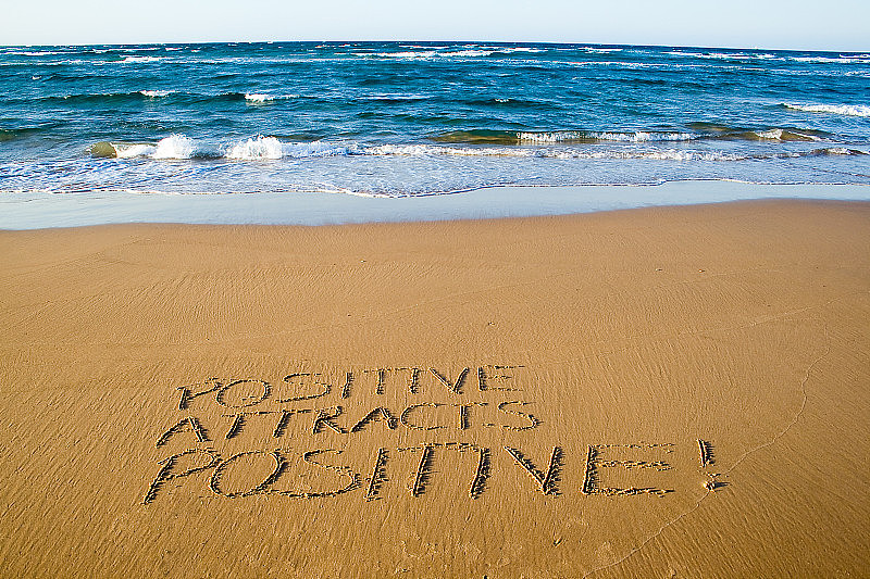 积极吸引积极的。写在沙滩上的创意动机概念。