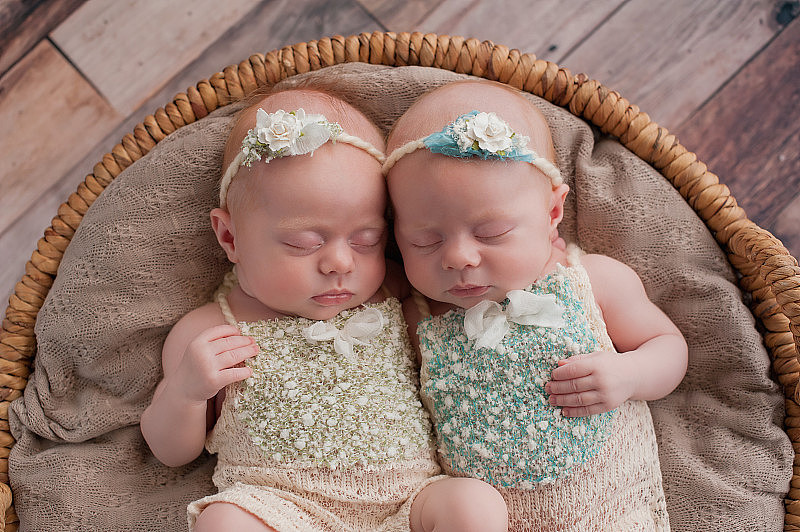 双胞胎女孩睡在柳条篮子里