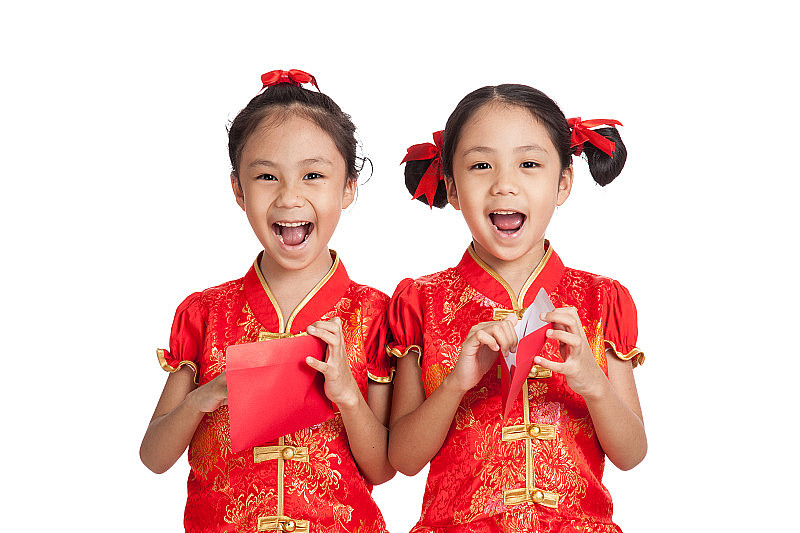 亚洲双胞胎女孩穿着中国旗袍和红包