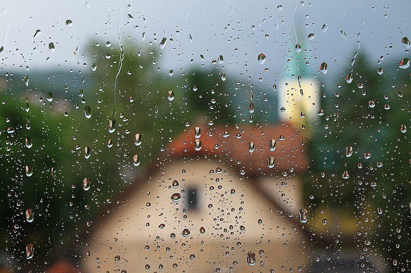 雨点落在窗户上，房子和教堂是背景