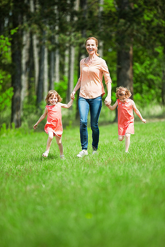 母亲和双胞胎女孩在大自然中行走