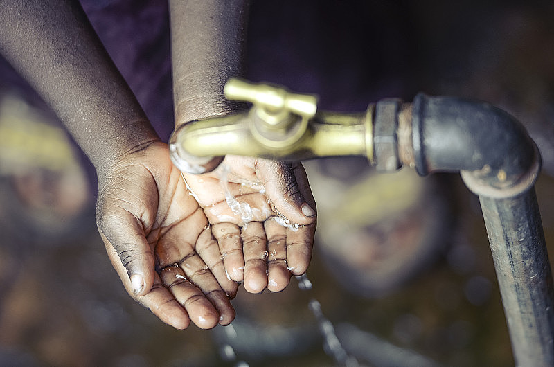巴马科，一名双手被水龙头盖住的非洲儿童