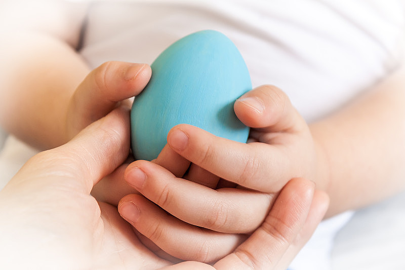 宝宝手里拿着蓝色的鸡蛋在妈妈的手里，特写