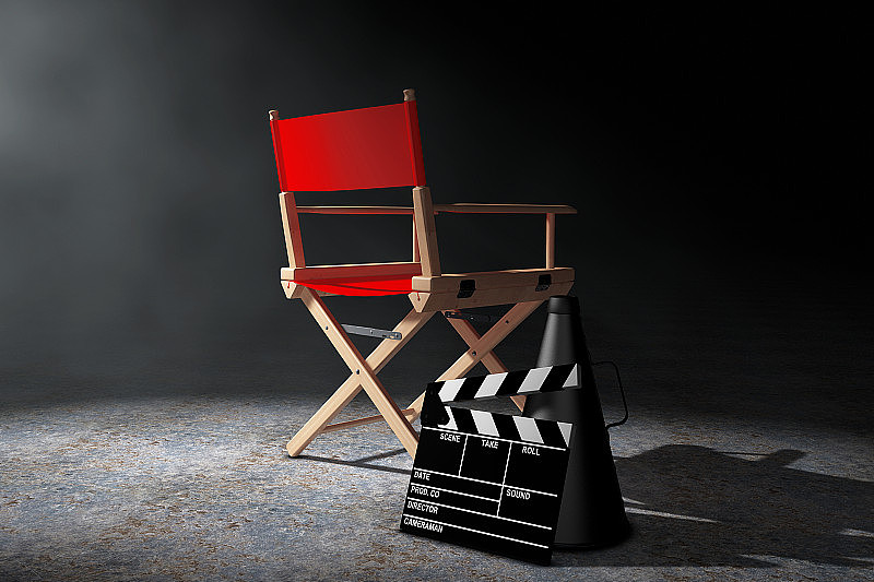 电影产业的概念。红色导演椅子，电影拍板和扩音器在体积光。三维渲染