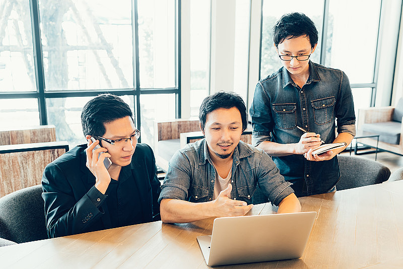 三名年轻的亚洲同事或大学生在咖啡厅或现代办公室参加严肃的商务会议或团队讨论，头脑风暴，创业项目演示或团队理念