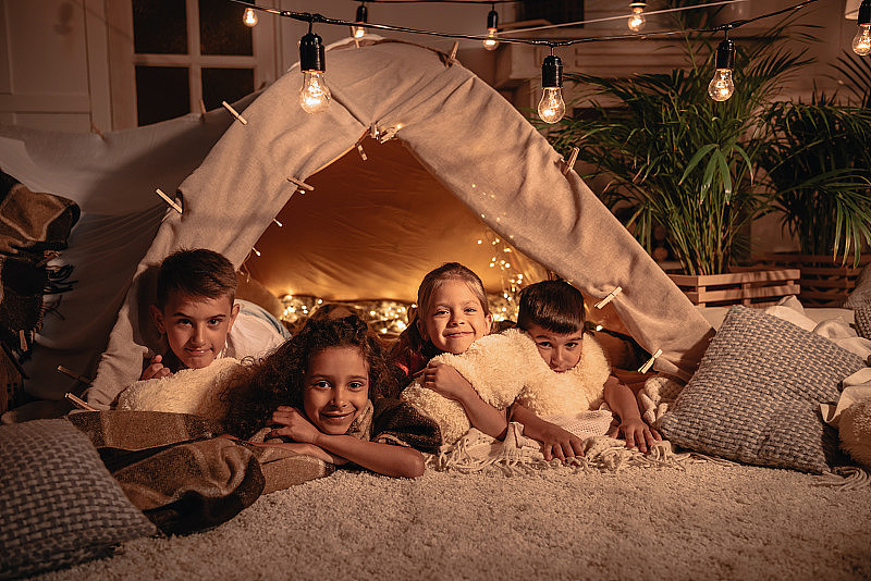多民族儿童在家中一起在手工帐篷中休息