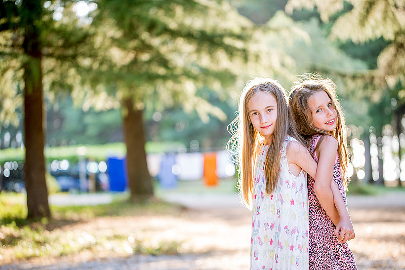 两个女孩背靠背在公园里的肖像