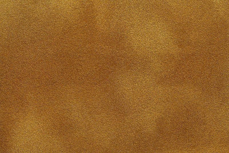 背景暗金色麂皮织物特写。黄色磨砂织物的天鹅绒哑光纹理