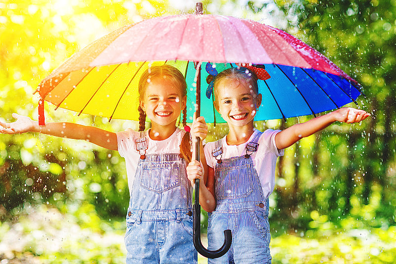 快乐有趣的姐妹双胞胎孩子女孩带伞