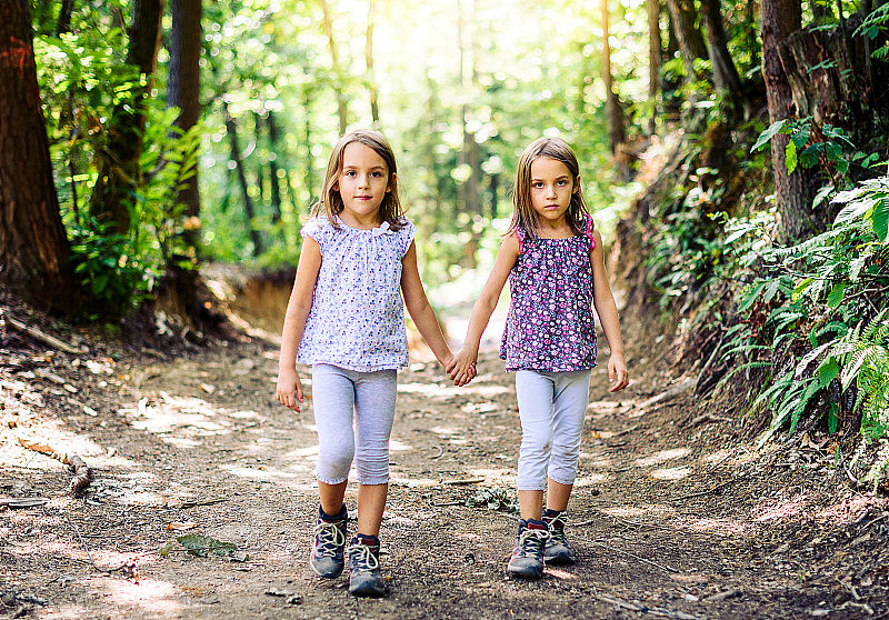 双胞胎女孩在山里徒步旅行。