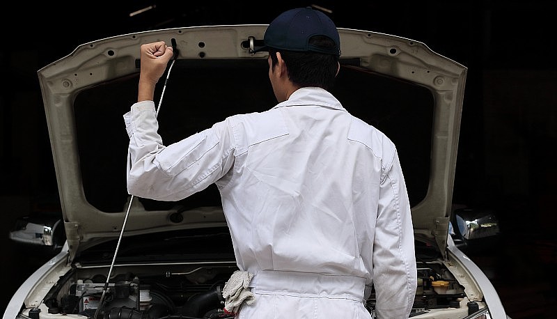 身穿制服的年轻专业机械师在修车厂举手的肖像。汽车保险的概念。