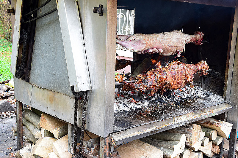 金属花园烤炉的壁炉上放着两只羊羔和一只猪
