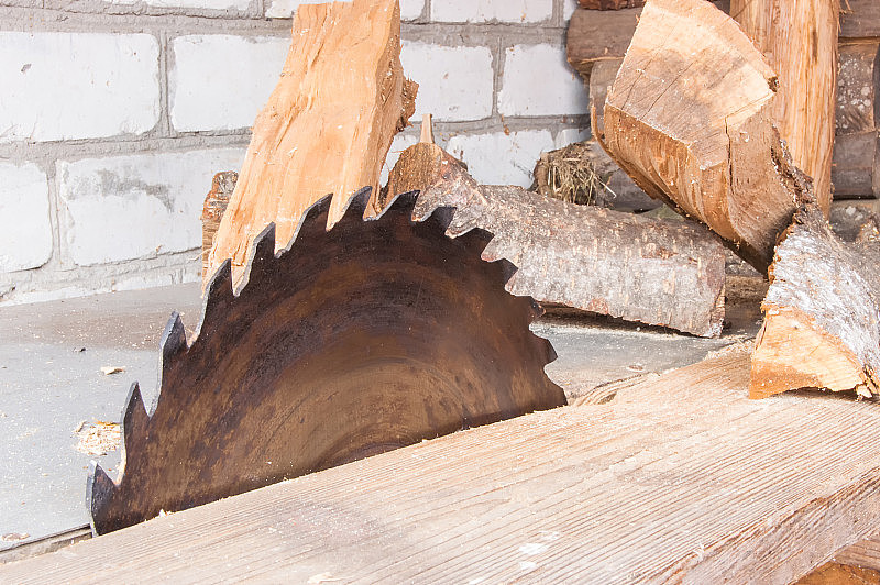 锯木厂木材和树干的圆锯。在桌子旁边的锯是用来加热炉子，壁炉和营火的柴火。木板或其它建筑材料的木材加工