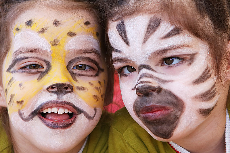 小女孩(双胞胎)的脸画得像猎豹和斑马