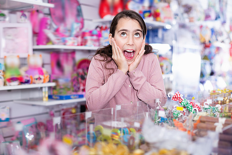 情绪化的小女孩在糖果店挑选糖果