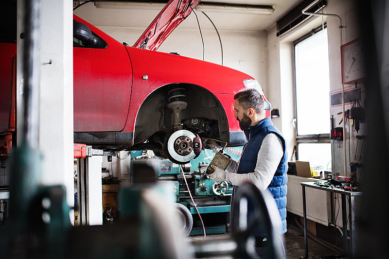 一名技工在修车厂修理汽车。