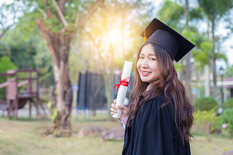 美丽迷人的亚洲女学生毕业生拿着证书，在毕业典礼上感到如此自豪和幸福