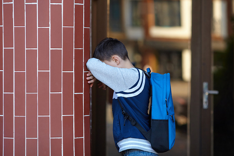 一个男生在学校的院子里靠墙哭