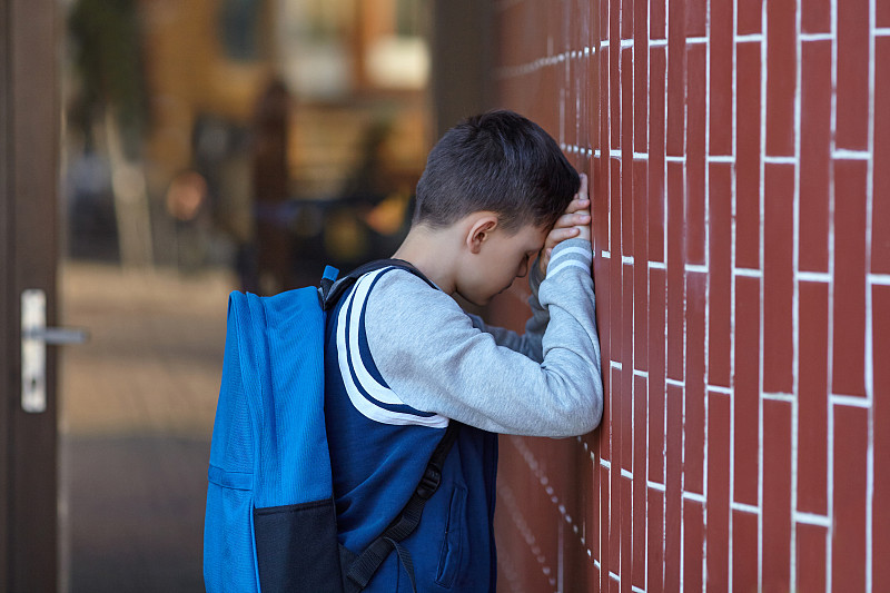 一个男生在学校的院子里靠墙哭