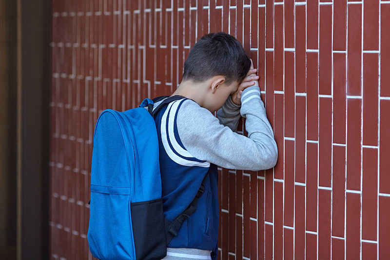 一个男生在学校的院子里靠墙哭