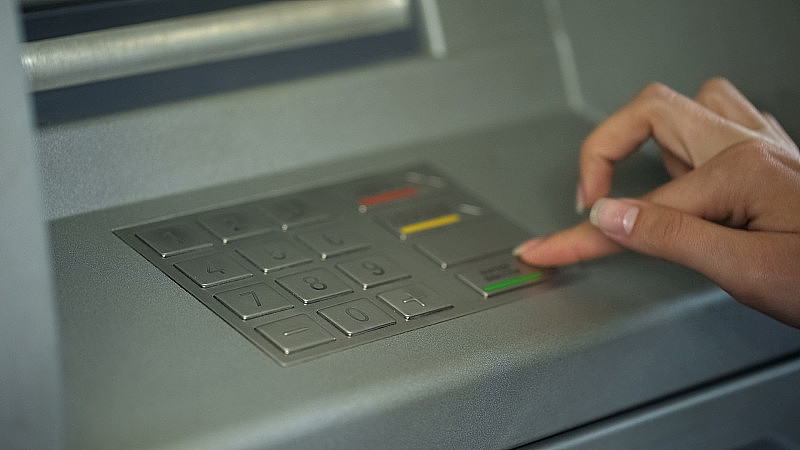 女士输入密码检查银行帐户和从自动取款机取钱