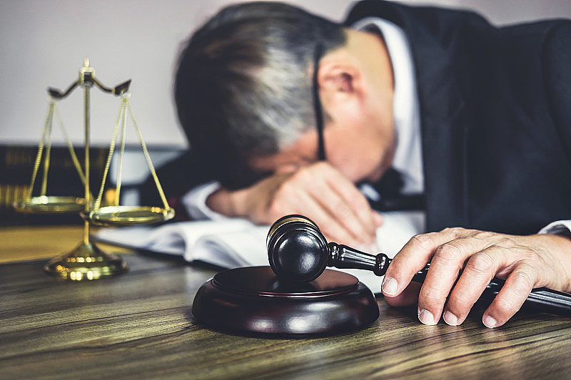 法官和律师们在木桌上用木槌，顾问或男律师在律师事务所努力处理文件时感到疲惫和偏头痛。法律、法律咨询和司法理念
