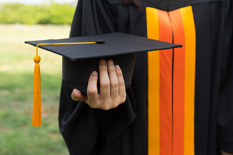 近距离聚焦大学毕业生持有学位证书和毕业帽庆祝毕业典礼。大学毕业生出示毕业证书。