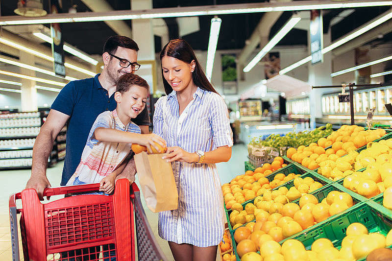 幸福的家庭和孩子和购物车购买食品在杂货店或超市