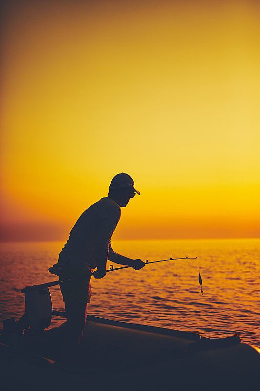 一个渔民的剪影在日落时间在公海上捕鱼。