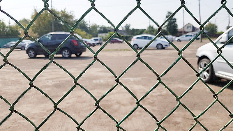 汽车在网状的篱笆后面。安全，有守卫的停车，罚款，逮捕的概念