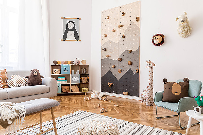 时尚斯堪的纳维亚风格的儿童室内设计，灰色沙发，现代的儿童攀岩墙，设计家具，毛绒玩具，泰迪熊和可爱的儿童配件。模拟了海报。模板。